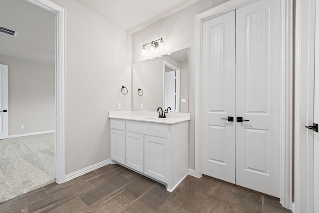 bathroom featuring visible vents, baseboards, and vanity