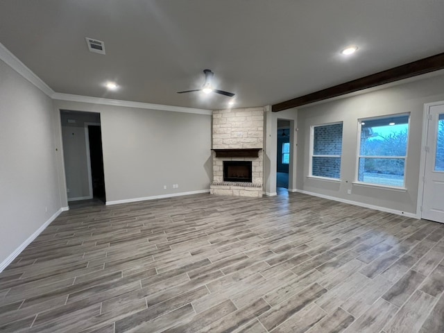 unfurnished living room with beamed ceiling, ceiling fan, ornamental molding, and a fireplace