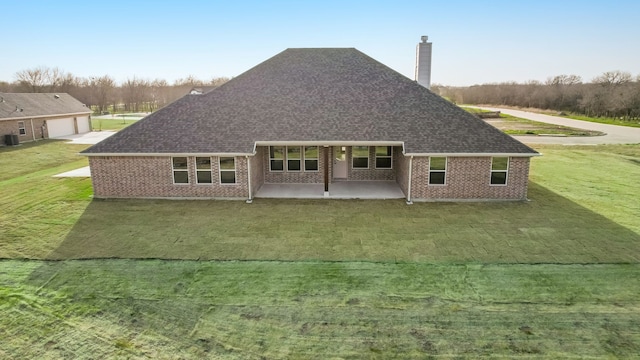 back of house with a yard, a shingled roof, a chimney, a patio area, and brick siding