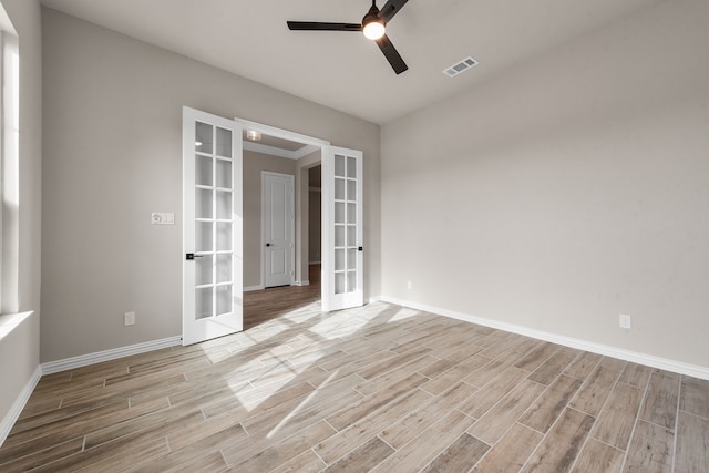 empty room with wood tiled floor, french doors, visible vents, and ceiling fan