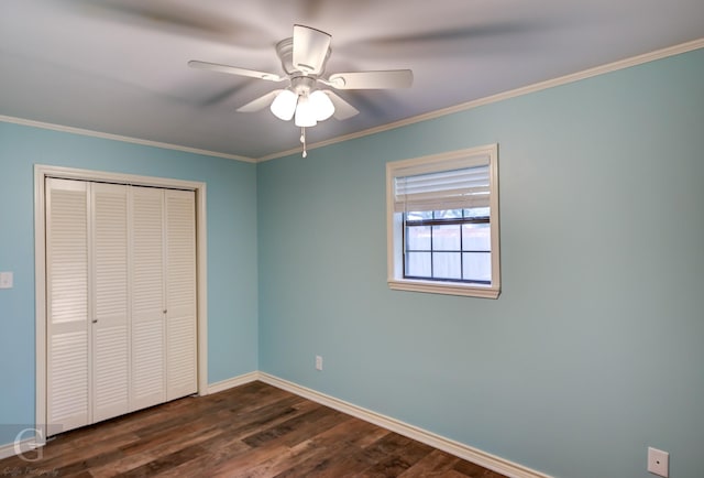 unfurnished bedroom with ornamental molding, dark wood-style flooring, ceiling fan, and a closet