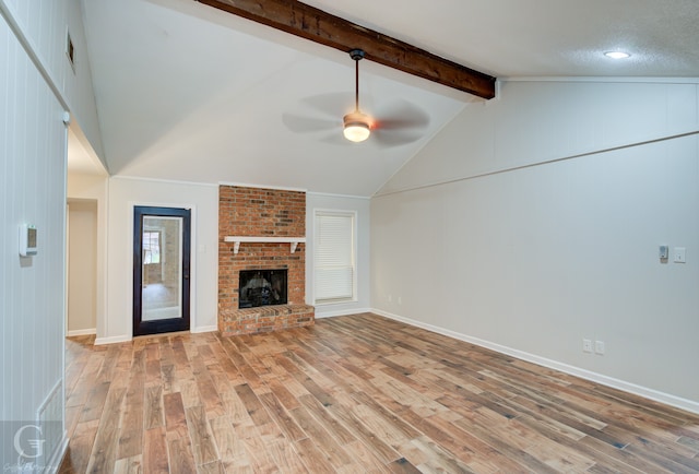 unfurnished living room with ceiling fan, lofted ceiling with beams, light hardwood / wood-style flooring, and a brick fireplace