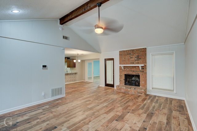 unfurnished living room with light wood-type flooring, a fireplace, lofted ceiling with beams, a textured ceiling, and ceiling fan