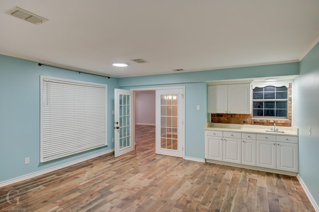 kitchen with visible vents, light countertops, light wood-type flooring, white cabinetry, and a sink