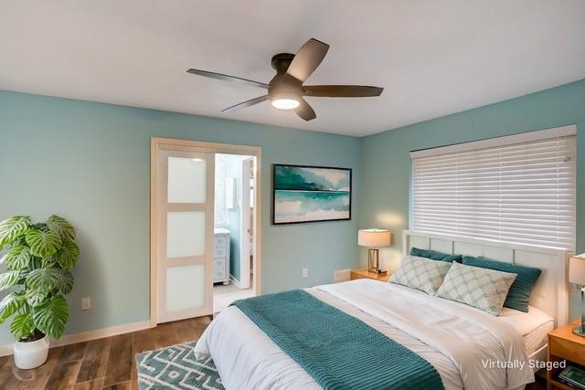 bedroom with dark wood-style floors, ceiling fan, ensuite bath, and baseboards