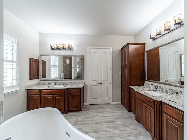 bathroom featuring vanity, vaulted ceiling, and a tub