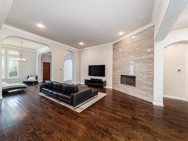 living room featuring ornamental molding, an inviting chandelier, a stone fireplace, and dark wood-type flooring