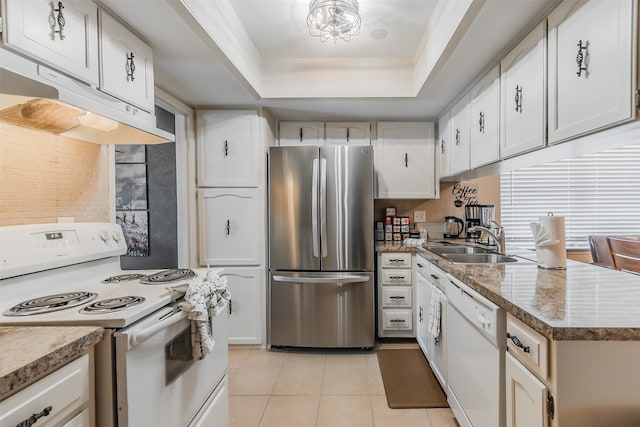 kitchen featuring white appliances, sink, a tray ceiling, white cabinetry, and light tile patterned floors