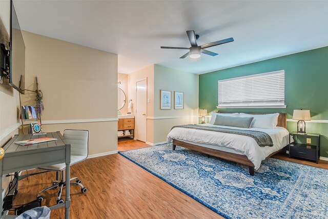 bedroom with ceiling fan, ensuite bath, and hardwood / wood-style floors