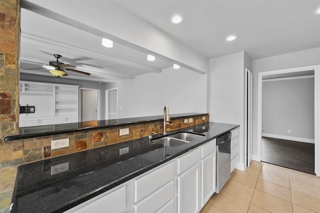 kitchen featuring dark stone countertops, sink, light tile patterned flooring, stainless steel dishwasher, and white cabinetry