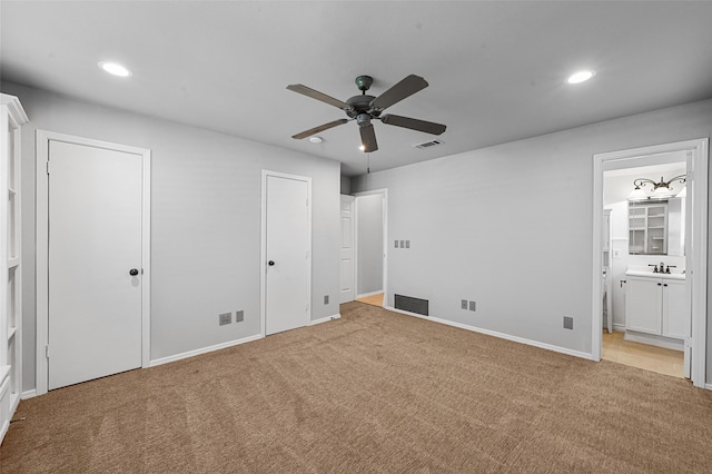 unfurnished bedroom with connected bathroom, sink, light colored carpet, and ceiling fan