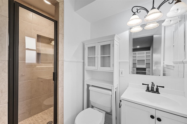 bathroom with toilet, a notable chandelier, vanity, and a shower with door