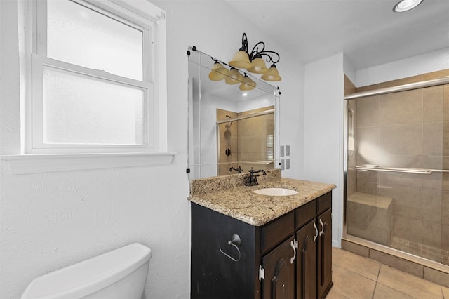 bathroom featuring vanity, toilet, tile patterned floors, and a shower with shower door