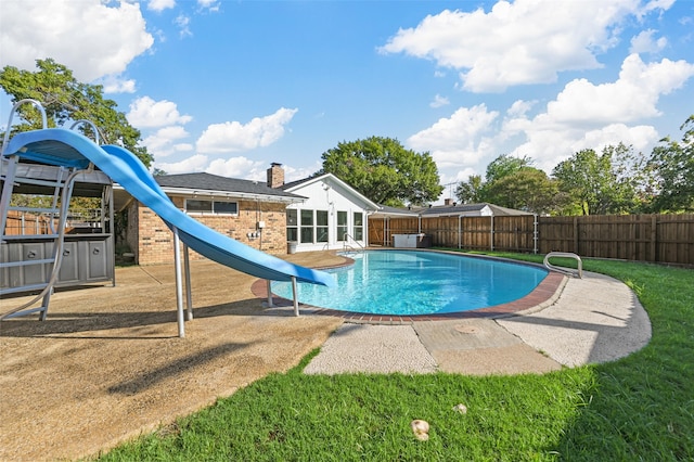 view of swimming pool with a patio area, a water slide, and a lawn