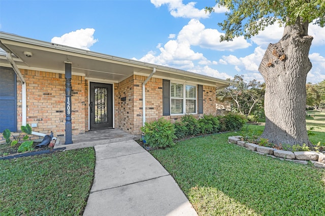 doorway to property featuring covered porch and a lawn