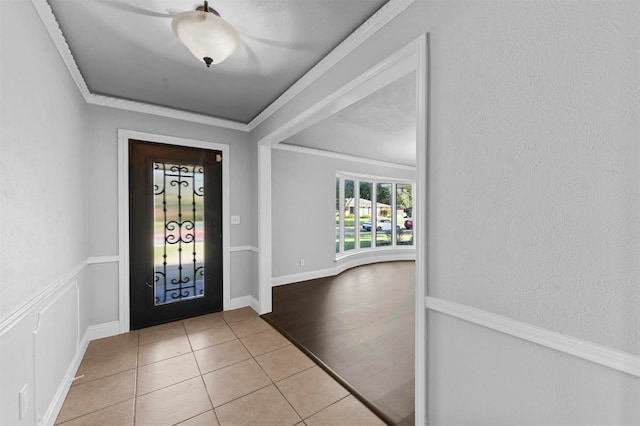 foyer with crown molding and light tile patterned flooring