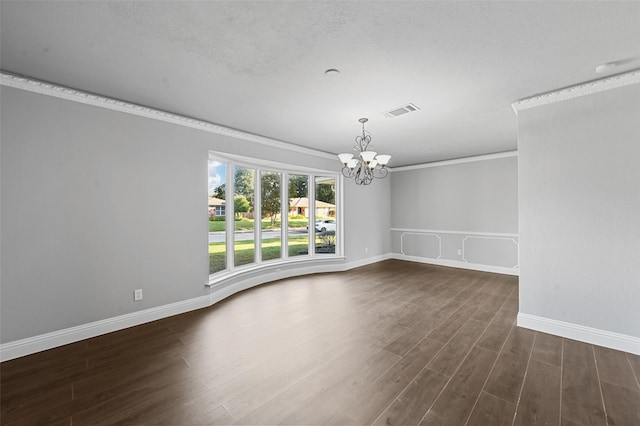 empty room featuring dark wood-type flooring, ornamental molding, a textured ceiling, and a chandelier