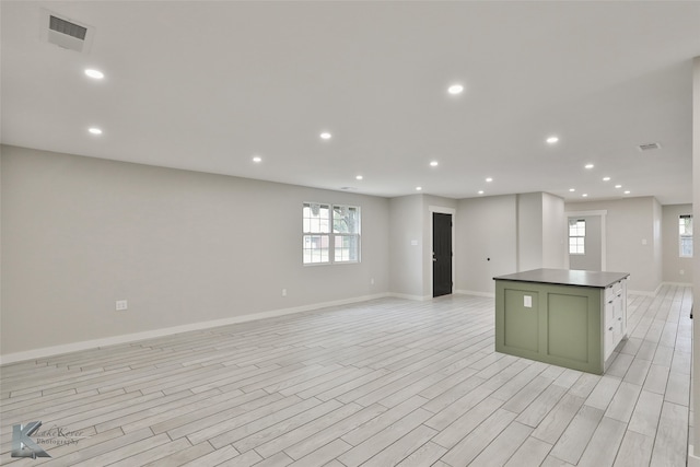 kitchen with green cabinets, a center island, light wood-type flooring, and white cabinets