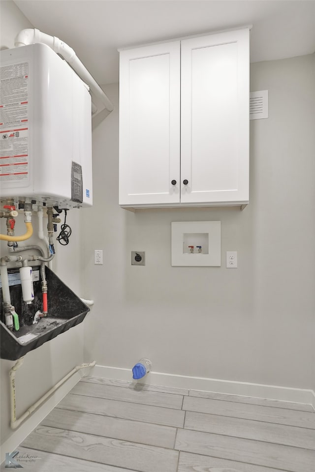 laundry area featuring light hardwood / wood-style floors, water heater, cabinets, and electric dryer hookup