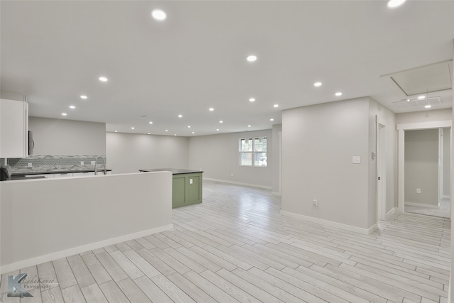 kitchen featuring light hardwood / wood-style floors, white cabinetry, sink, and backsplash