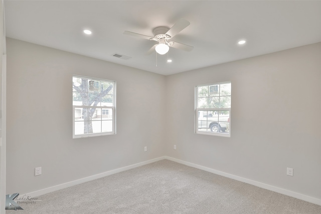 carpeted spare room featuring a healthy amount of sunlight and ceiling fan