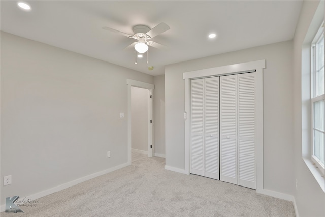 unfurnished bedroom with light colored carpet, a closet, and ceiling fan