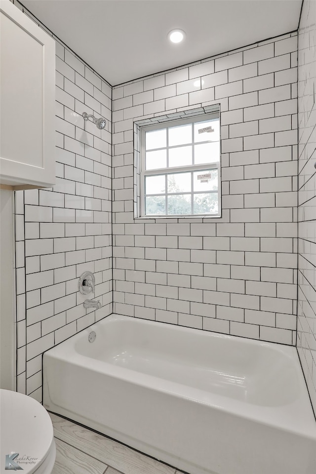 bathroom featuring toilet and tiled shower / bath