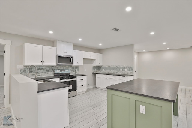 kitchen with appliances with stainless steel finishes, white cabinetry, light wood-type flooring, and backsplash