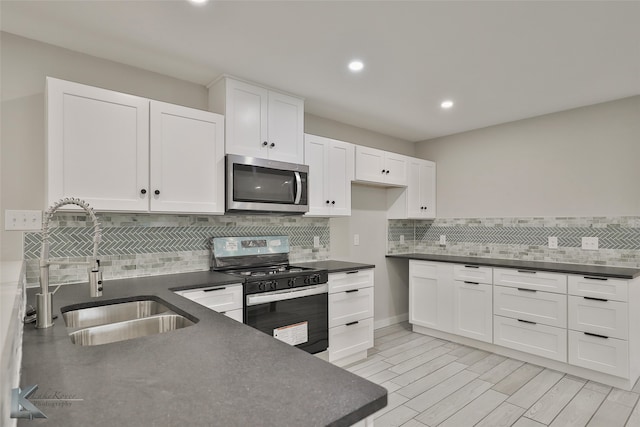 kitchen with decorative backsplash, black range, sink, and white cabinetry