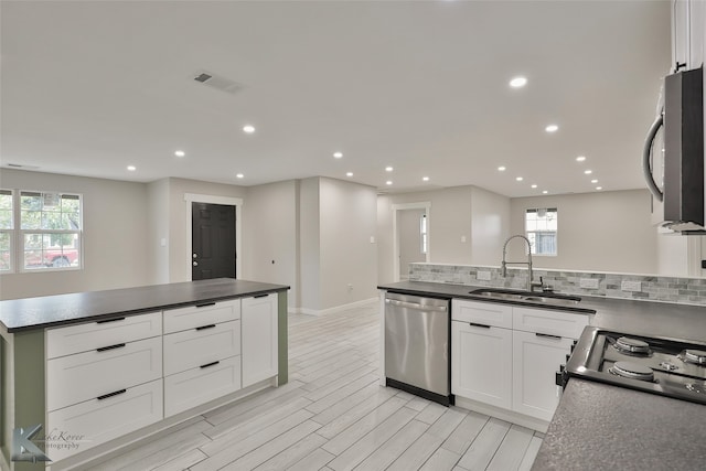 kitchen featuring appliances with stainless steel finishes, white cabinetry, sink, and plenty of natural light