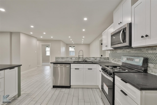 kitchen with sink, stainless steel appliances, white cabinets, decorative backsplash, and light hardwood / wood-style flooring