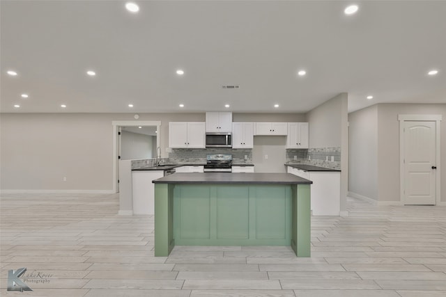 kitchen featuring decorative backsplash, white cabinetry, stainless steel appliances, and a center island