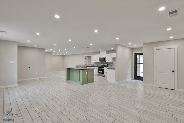 kitchen with a kitchen island, light hardwood / wood-style flooring, green cabinets, white cabinets, and appliances with stainless steel finishes