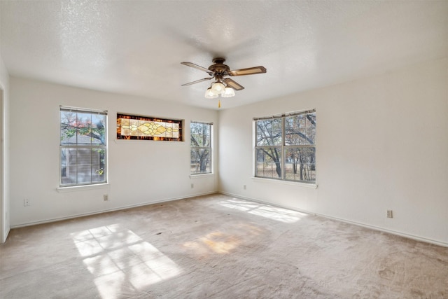 carpeted spare room featuring a wealth of natural light, ceiling fan, and a textured ceiling