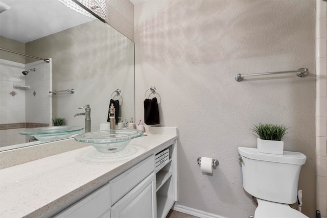 bathroom with vanity, tiled shower, and toilet