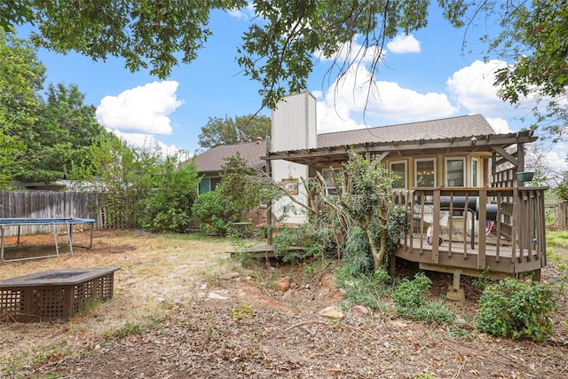 view of yard with a wooden deck, a pergola, and a trampoline