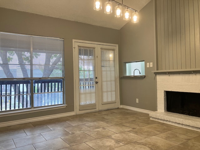 entryway featuring french doors, a textured ceiling, a fireplace, and vaulted ceiling