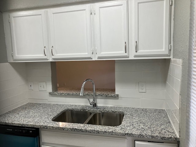 kitchen with light stone counters, backsplash, white cabinetry, dishwasher, and sink