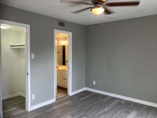 unfurnished bedroom featuring a spacious closet, hardwood / wood-style flooring, and a closet