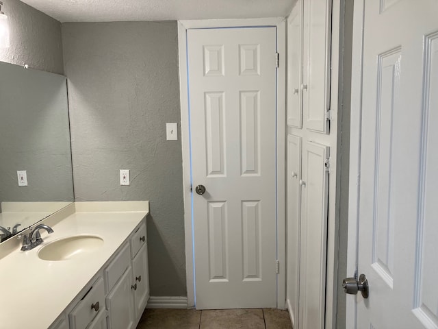 bathroom with vanity, a textured ceiling, and tile patterned flooring