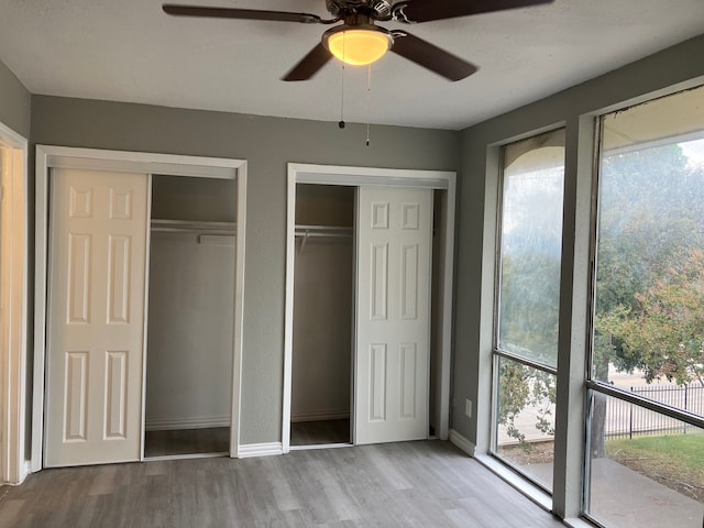 unfurnished bedroom featuring ceiling fan, light hardwood / wood-style floors, two closets, and access to exterior