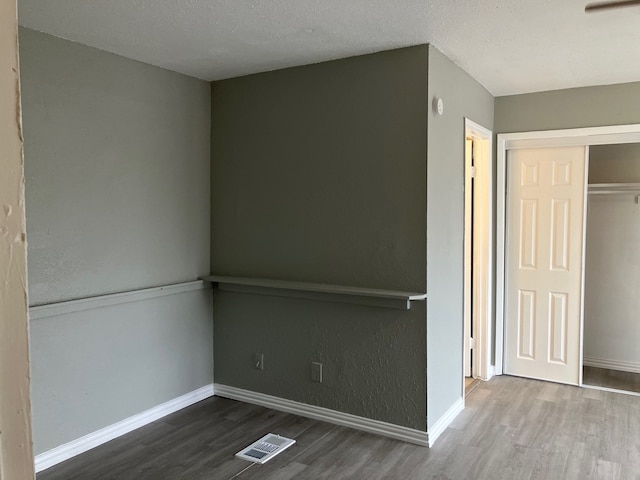 empty room with hardwood / wood-style floors and a textured ceiling