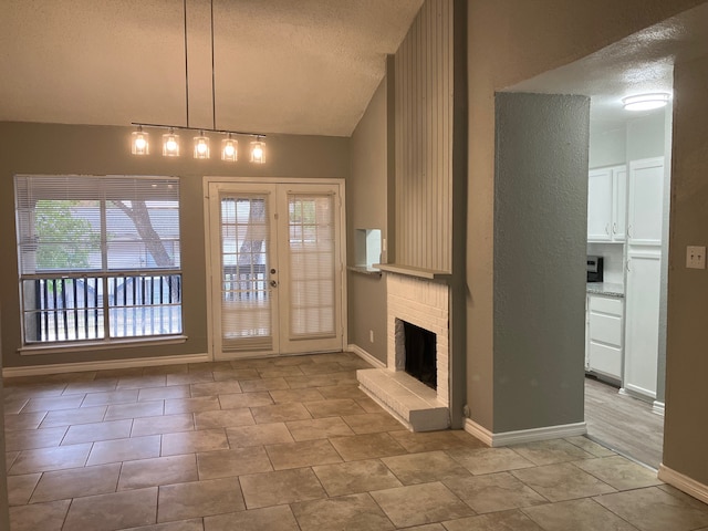 unfurnished living room with french doors, vaulted ceiling, a brick fireplace, and a textured ceiling