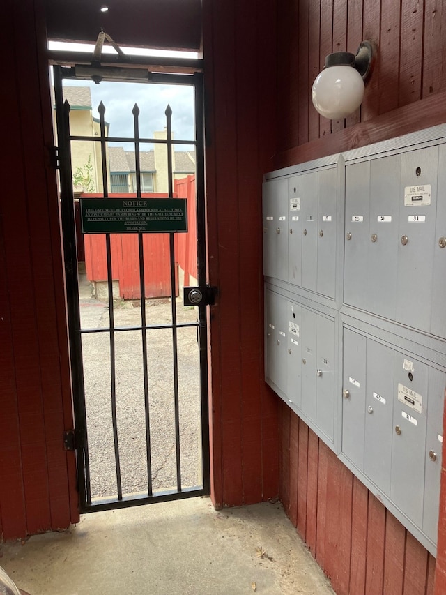 exterior details with wooden walls, concrete flooring, and mail boxes