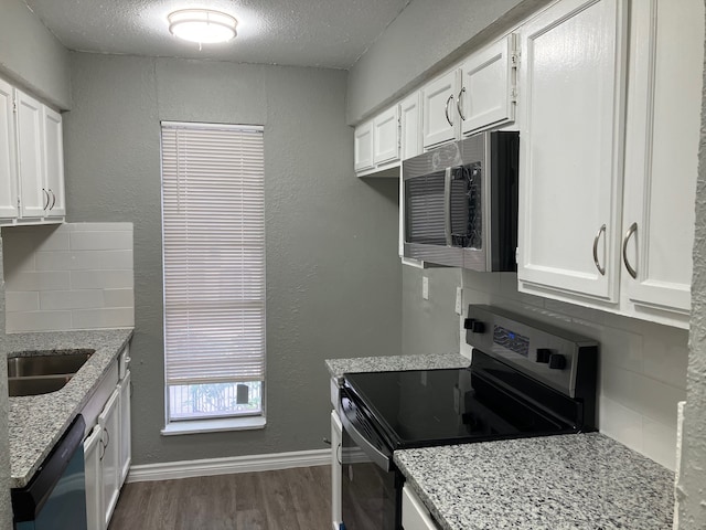 kitchen with backsplash, white cabinetry, appliances with stainless steel finishes, light stone counters, and dark hardwood / wood-style flooring