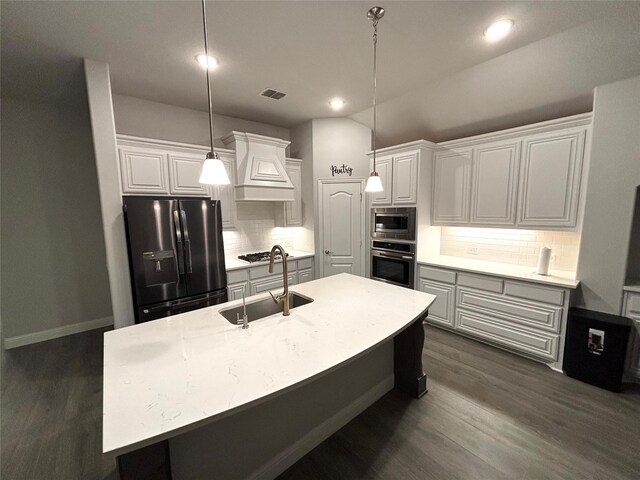 kitchen with sink, stainless steel appliances, premium range hood, an island with sink, and pendant lighting