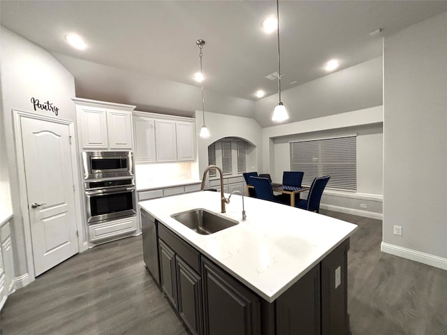 kitchen featuring sink, hanging light fixtures, stainless steel appliances, an island with sink, and lofted ceiling