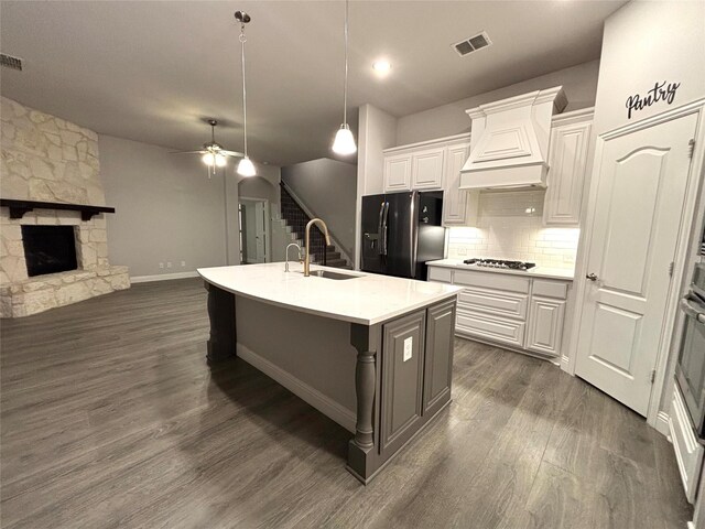 kitchen with a center island with sink, dark hardwood / wood-style floors, black fridge with ice dispenser, and white cabinets