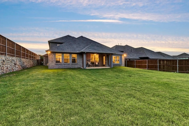 back house at dusk with a yard and a patio area