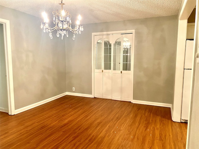 unfurnished dining area with hardwood / wood-style floors, a notable chandelier, and a textured ceiling